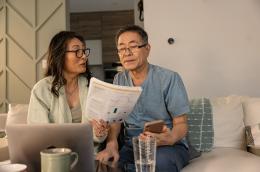 A couple sits on a couch looking at paperwork