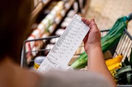 Person holds a receipt above their grocery basket