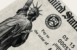 An illustration of the Statue of Liberty is featured prominently on a close-up of a US Department of the Treasury check, next to a Bureau of the Fiscal Service official stamp above the text "Pay to the order of."