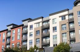 A row of midsize, modern apartment buildings on a clear, sunny day.