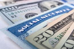 A close-up of an American Social Security Card fanned between an American $5, $100, and two $20 bills. 