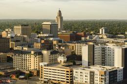 A high shot of an urban area with many different kinds of buildings, including a tall tower, apartments, and a parking garage.