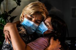 Two women hug while wearing masks