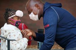 A father helps his daughter with her jacket while dropping her off for her first day of 1st grade at the Lincoln-Hancock Community School in Quincy, MA on September 17, 2020.