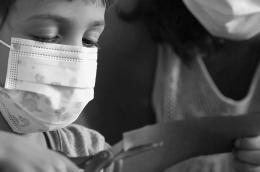Child does crafts while wearing a mask
