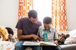A child and his father read together