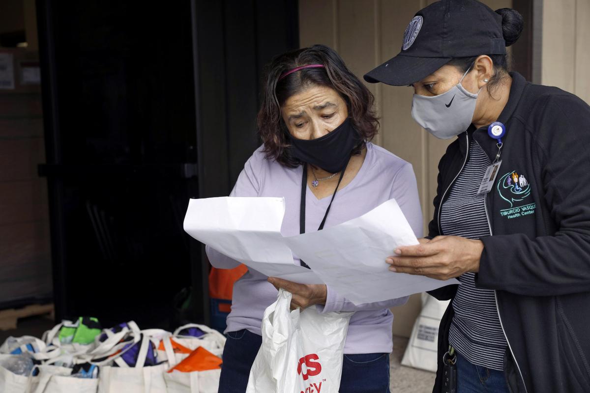  Promotora Julieta Martinez (in the gray mask) helps divide the list of families who will receive the supplies.