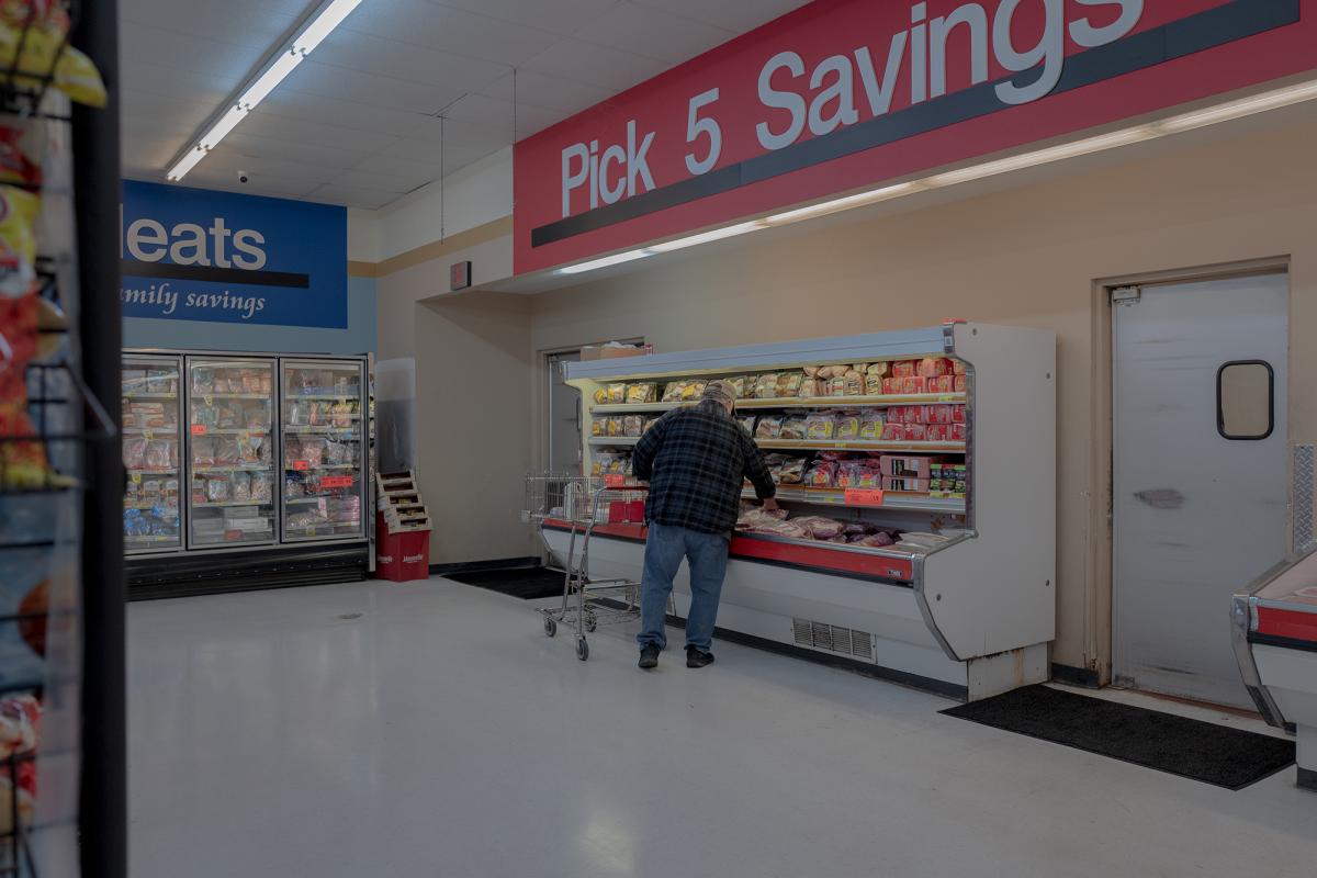 A man perusing the meat selection at a grocery store.