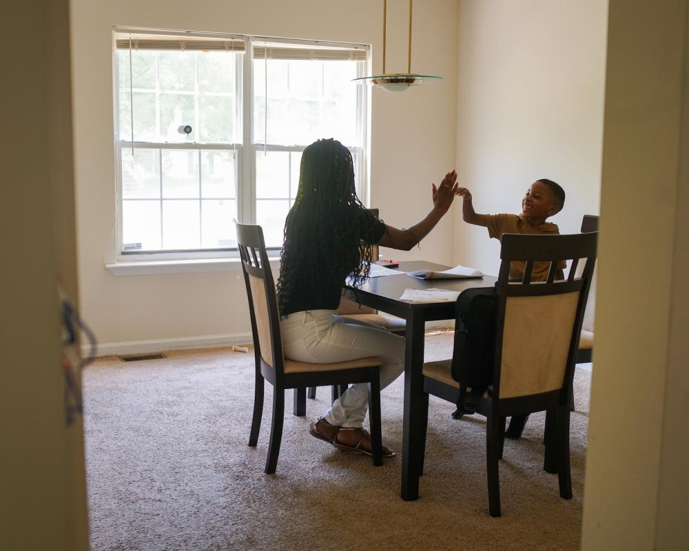 Gina and Kayden high-five after he correctly defines the word on a flash card.